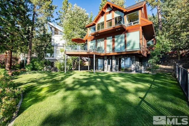 rear view of property featuring a balcony and a yard