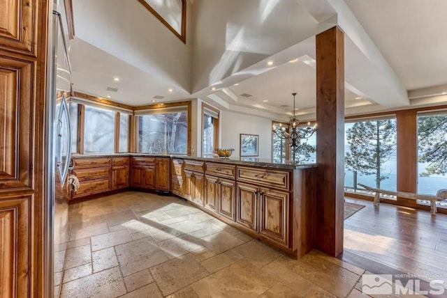 kitchen with hanging light fixtures, dark stone counters, light hardwood / wood-style floors, sink, and a chandelier