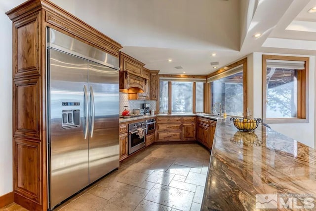 kitchen featuring sink, light tile floors, light stone counters, appliances with stainless steel finishes, and tasteful backsplash