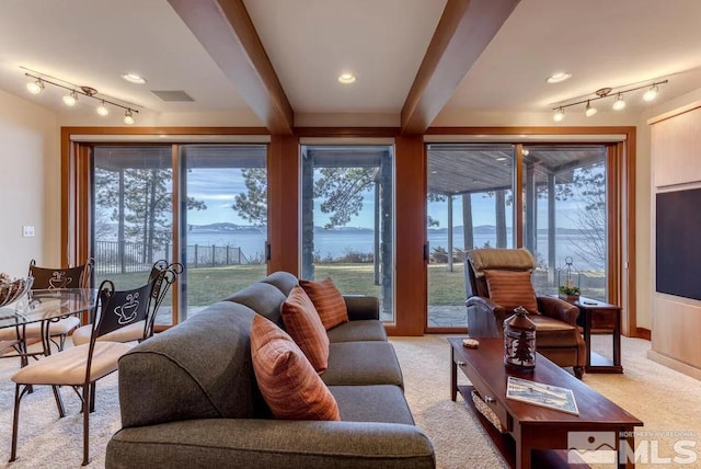 living room with track lighting, light carpet, beam ceiling, and a water view