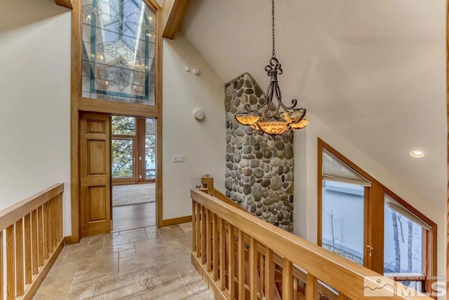 corridor featuring high vaulted ceiling, an inviting chandelier, and light tile floors