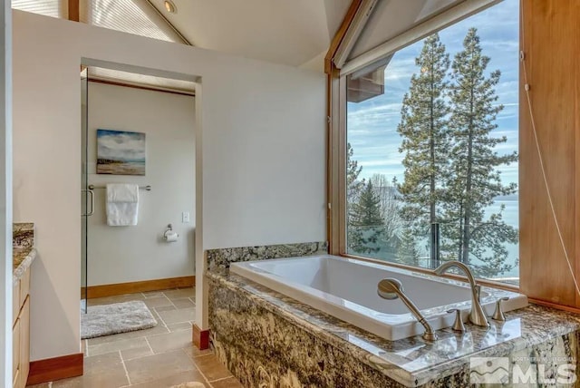 bathroom with a relaxing tiled bath, vanity, and tile flooring