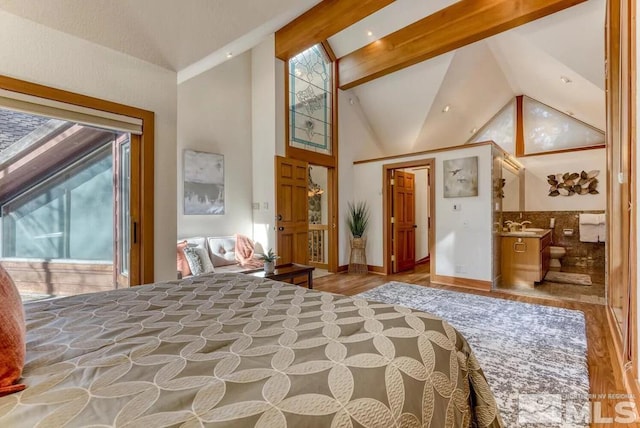 bedroom featuring high vaulted ceiling, light hardwood / wood-style floors, beam ceiling, and ensuite bath