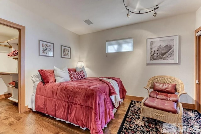 bedroom with light hardwood / wood-style flooring and track lighting