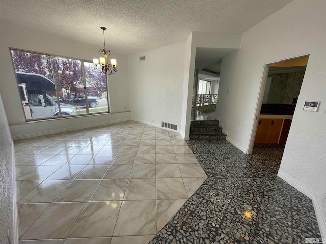 tiled empty room featuring a notable chandelier and a textured ceiling