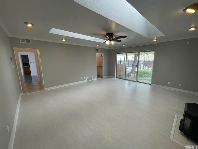 spare room featuring ceiling fan, a fireplace, a textured ceiling, a skylight, and crown molding