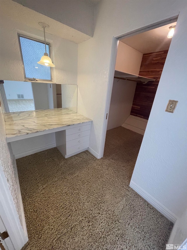 unfurnished office featuring built in desk and dark colored carpet