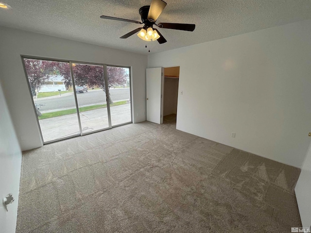 empty room with light colored carpet, ceiling fan, and a textured ceiling