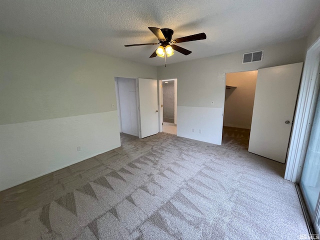 unfurnished bedroom featuring light colored carpet, a closet, ceiling fan, and a textured ceiling