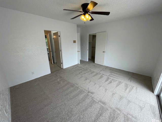 unfurnished bedroom featuring light carpet, a textured ceiling, and ceiling fan