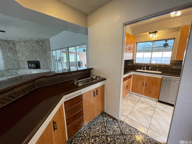 kitchen featuring backsplash, ceiling fan, sink, light tile floors, and dishwasher