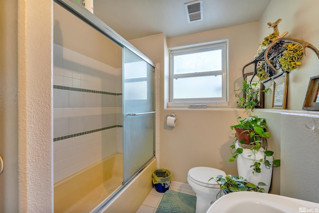 bathroom featuring enclosed tub / shower combo, toilet, and tile floors