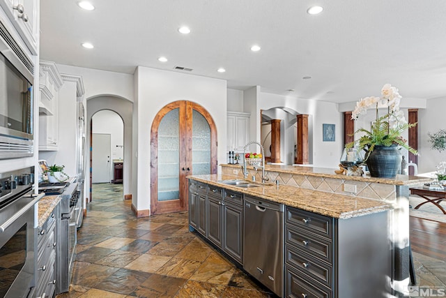 kitchen featuring an island with sink, appliances with stainless steel finishes, sink, white cabinets, and dark hardwood / wood-style flooring