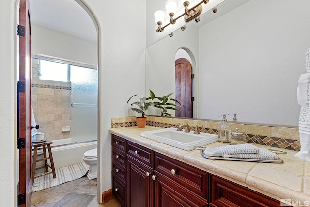 full bathroom with bath / shower combo with glass door, vanity, toilet, and tile floors