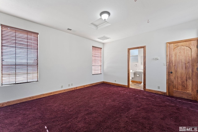 unfurnished bedroom with connected bathroom and dark carpet