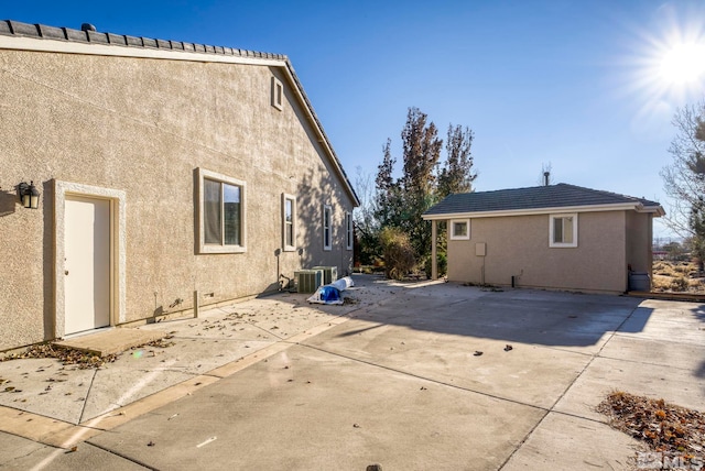 view of side of home with central AC unit and a patio