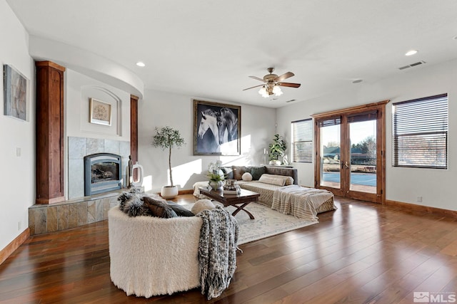 living room featuring french doors, ceiling fan, a tile fireplace, and dark wood-type flooring