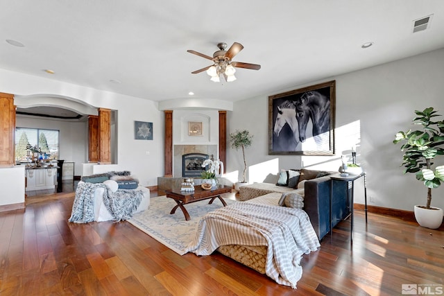 living room featuring ceiling fan, dark hardwood / wood-style flooring, and a fireplace