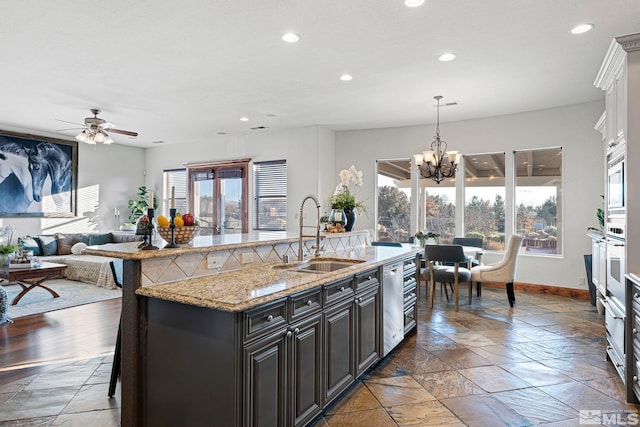 kitchen featuring plenty of natural light, ceiling fan with notable chandelier, a breakfast bar area, and sink