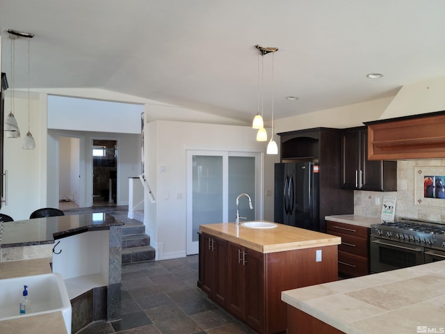 kitchen with black refrigerator, pendant lighting, double oven range, a kitchen island with sink, and vaulted ceiling