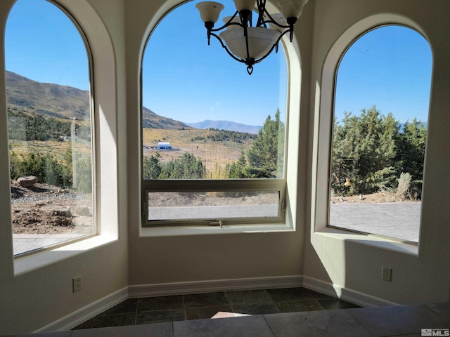 empty room featuring a mountain view, dark tile floors, and a chandelier