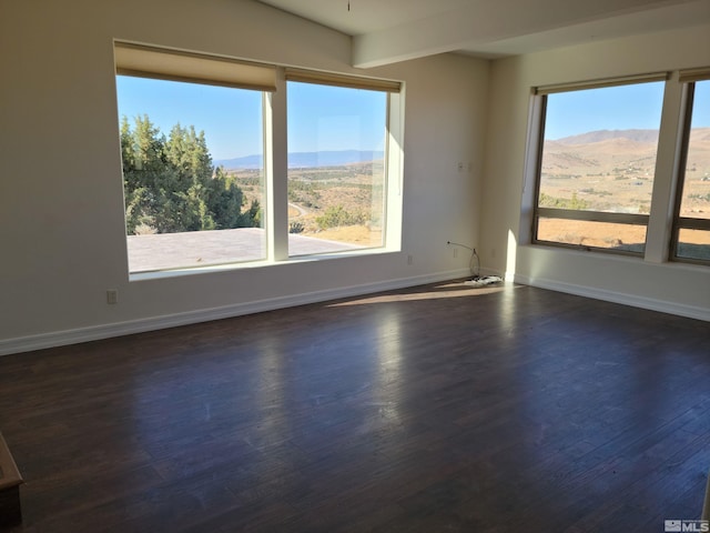 empty room with a mountain view and dark hardwood / wood-style floors