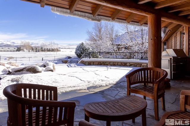 snow covered patio featuring area for grilling and a grill