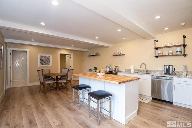 kitchen featuring white cabinetry, beamed ceiling, a kitchen breakfast bar, light wood-type flooring, and dishwasher