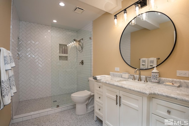 bathroom with toilet, tile floors, a tile shower, and vanity