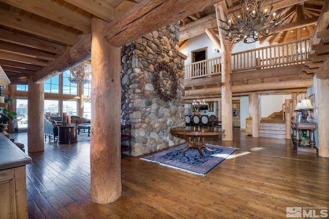 unfurnished living room with a chandelier, beam ceiling, wooden ceiling, a high ceiling, and dark hardwood / wood-style flooring