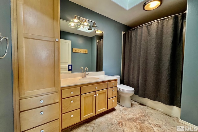 bathroom featuring a skylight, tile floors, toilet, and vanity with extensive cabinet space