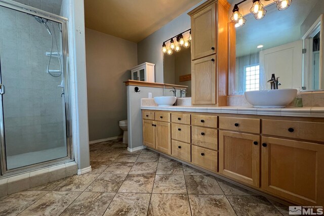 bathroom featuring dual bowl vanity, toilet, tile floors, and an enclosed shower
