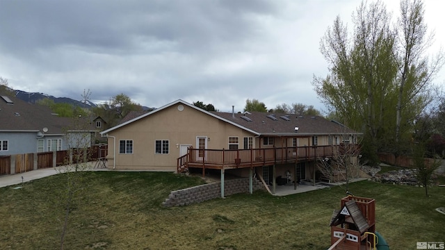 rear view of house with a deck, a lawn, and a patio