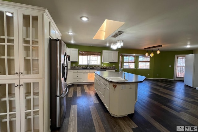 kitchen featuring dark hardwood / wood-style floors, a kitchen island with sink, white fridge, stainless steel fridge with ice dispenser, and decorative light fixtures