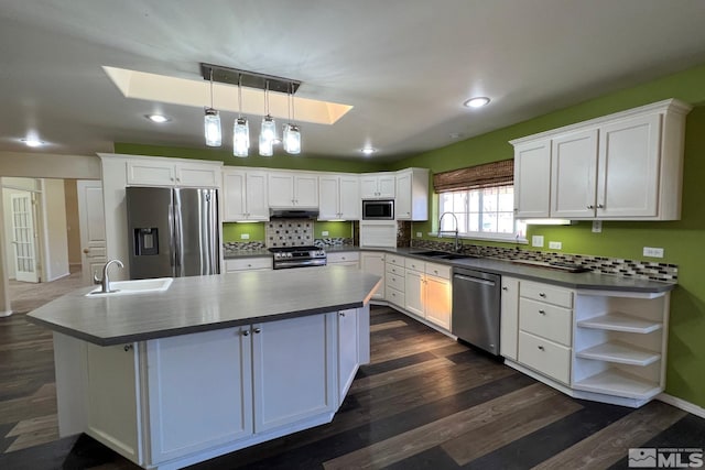 kitchen featuring a kitchen island, stainless steel appliances, white cabinets, and a skylight