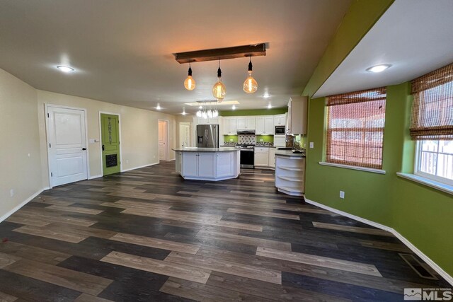 kitchen featuring hanging light fixtures, white cabinetry, dark wood-type flooring, a kitchen island with sink, and appliances with stainless steel finishes