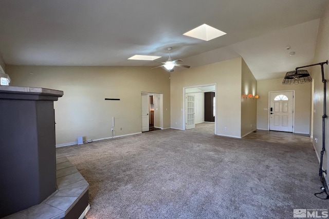 carpeted empty room with ceiling fan and lofted ceiling with skylight