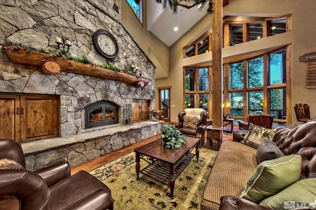 living room featuring high vaulted ceiling, hardwood / wood-style floors, and a stone fireplace