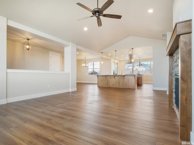 unfurnished living room with vaulted ceiling, dark hardwood / wood-style floors, and ceiling fan with notable chandelier