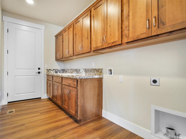 laundry area with hookup for a washing machine, cabinets, electric dryer hookup, and light hardwood / wood-style flooring