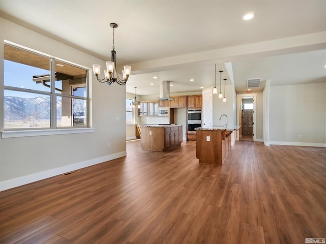 kitchen with a center island with sink, dark hardwood / wood-style flooring, and decorative light fixtures