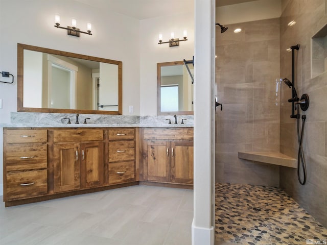 bathroom with tile floors, tiled shower, and dual bowl vanity