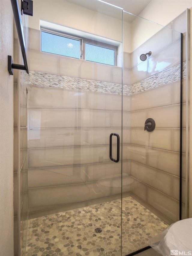 bathroom featuring toilet and a shower with door