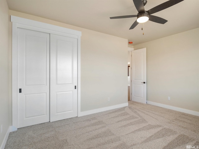 unfurnished bedroom featuring light carpet, a closet, and ceiling fan