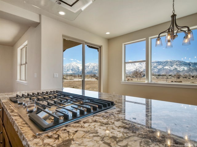 kitchen with hanging light fixtures, stainless steel gas cooktop, a mountain view, a chandelier, and light stone counters