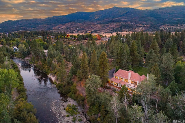 aerial view at dusk featuring a water and mountain view