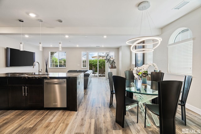 kitchen featuring stainless steel dishwasher, an inviting chandelier, hanging light fixtures, light wood-type flooring, and sink