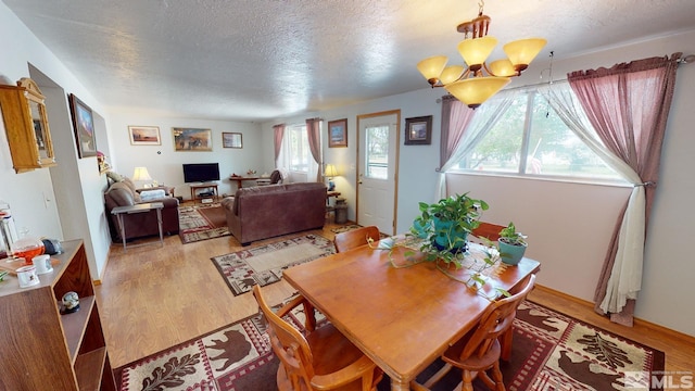 dining area with light hardwood / wood-style flooring, a chandelier, and a textured ceiling