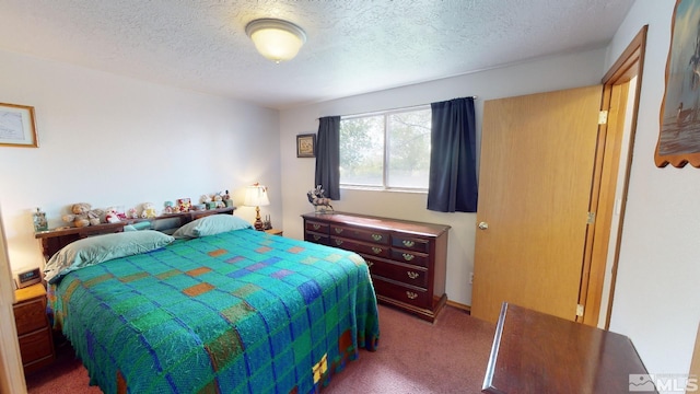 bedroom featuring a textured ceiling and dark colored carpet