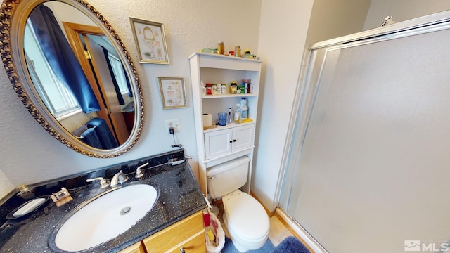 bathroom featuring toilet, large vanity, and an enclosed shower